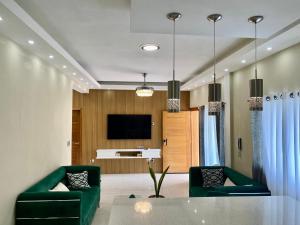 un soggiorno con 2 sedie verdi e una TV di Elegante Apartamento A 100 mts la playa de los Minos RSJ a Río San Juan