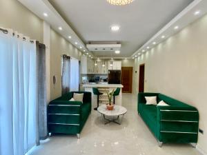 un soggiorno con 2 divani verdi e un tavolo di Elegante Apartamento A 100 mts la playa de los Minos RSJ a Río San Juan