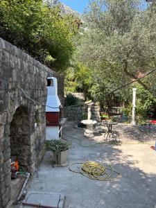 podwórko z kamienną ścianą i wężem w obiekcie Vila Violeta w mieście Donji Morinj