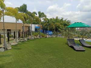 a park with a bench and an umbrella and grass at Apartamento cómodo, luz natural, zonas comunes, piscinas traer gorro, wifi, parqueadero en el Quindío in La Tebaida