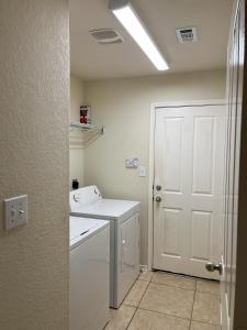 uma lavandaria com uma máquina de lavar roupa e uma porta branca em Cozy & spacious 3 bed home North San Antonio - Stone Oak area em Bulverde