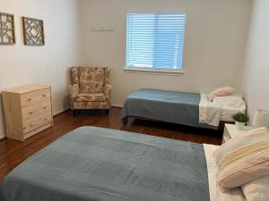 um quarto com 2 camas, uma cadeira e uma janela em Cozy & spacious 3 bed home North San Antonio - Stone Oak area em Bulverde