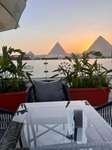 Aurora Pyramids Hotel في القاهرة: طاولة على شرفة مطلة على الاهرامات