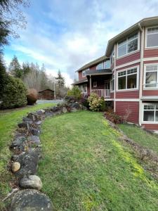 a house with a grass yard in front of it at Skyview Apartment at Otter Point in Sooke