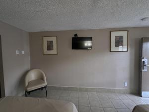 um quarto com uma cadeira e uma televisão na parede em Hotel Galaxy em Las Vegas