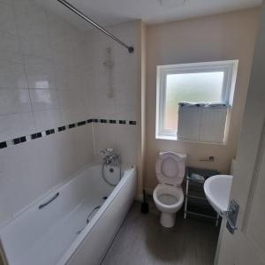 a bathroom with a tub and a toilet and a sink at 3 bed house - Milton Keynes - Countess Plaza in Broughton