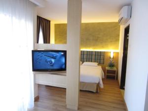a bedroom with a bed and a flat screen tv at Bella Vista Waterfront Resort, Kuah Langkawi in Kuah