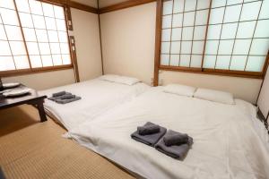 two twin beds in a room with windows at 五十岚民宿 地铁站步行4分 免费高速 WI-FI TraditionCozy Japanese Villa in Ikebukuro 6mins St with Hight speed WIFI in Tokyo