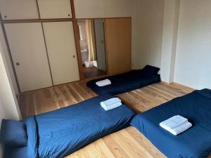 twee bedden in een kamer met blauwe lakens bij ペンションAloalo in Shirahama