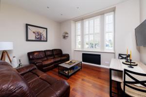 uma sala de estar com um sofá de couro e uma televisão em 1 Old Edinburgh Court em Inverness