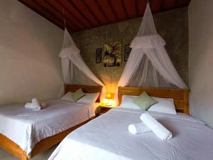 2 Betten in einem Zimmer mit weißer Bettwäsche in der Unterkunft Artomoro Bali in Munduk