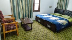 a bedroom with a bed and a table and a chair at Al-Bilad Guest House in Srinagar