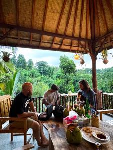 eine Gruppe von Menschen, die um einen Tisch sitzen in der Unterkunft Artomoro Bali in Munduk