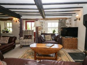 sala de estar con muebles de cuero y TV en Moss Side Farm Cottage, en lower hawthwaite