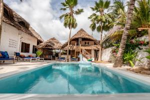 a pool in front of a house with palm trees at Mamamapambo Boutique Hotel in Jambiani