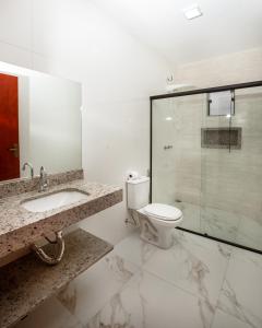 ein Badezimmer mit Toilette und Glasdusche in der Unterkunft ECOLETRAS APART - HOTEL - SÃO THOMÉ DAS LETRAS Mg in São Thomé das Letras