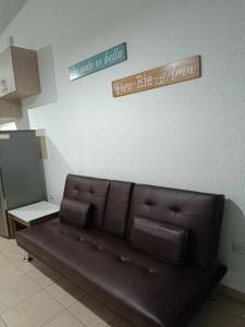a brown leather couch in a room with a sign at MINI CASA ECOTERRA SANTA ANA in Santa Ana