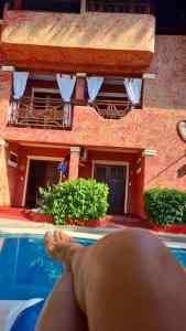 a person with their feet in a swimming pool in front of a house at Hotel El Rancho Sosua in Sos&uacute;a