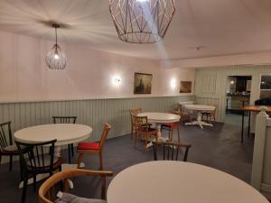 ein Restaurant mit Tischen, Stühlen und einem Kronleuchter in der Unterkunft Pension Zum grünen Kakadu in Göhren