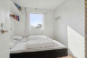 a bed with white sheets in a room with a window at Idyllic Holiday Home Near Cliffs And Beach in Gudhjem