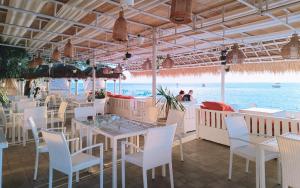 a restaurant with white tables and chairs and the ocean at Unzipp Bungalows Gili Air in Gili Islands