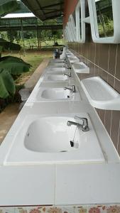a row of white sinks in a public restroom at ศูนย์สัมมนาอาร์มทอง in Ban Khlong Kathon