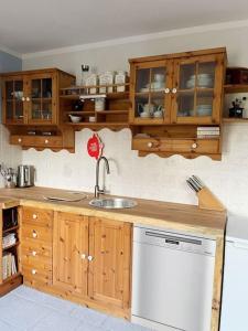 uma cozinha com armários de madeira e uma máquina de lavar louça branca em Casa Angres - Lüneburger Heide 