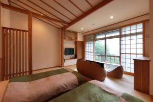 a bedroom with a large bed and a large window at Akagi Onsen Hotel in Maebashi