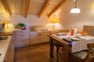 uma cozinha com uma mesa de madeira e uma toalha de mesa branca em Haus Lesch - Stilvolle Appartements mit tollem Bergblick in Kreuth am Tegernsee em Kreuth