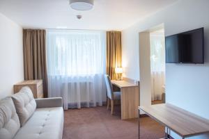 a hotel room with a couch and a table and a desk at Willa Sonata in Karpacz