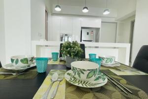 a dining room table with plates and utensils on it at Jazz Suites Seaview with Bathtub - 2901 in Tanjong Tokong