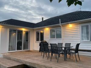 a deck with chairs and a table on a house at Rata Karaka Bach in Ngunguru