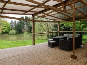 una terraza de madera con pérgola y muebles. en Bracken Cottage en Okehampton