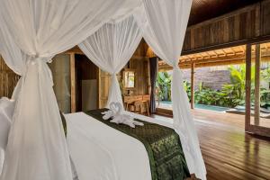 - une chambre dotée d'un lit avec des rideaux blancs dans l'établissement The Ulon Ubud Villa, à Ubud