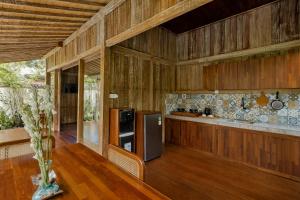 Il comprend une cuisine dotée de murs en bois, de parquet et d'un réfrigérateur. dans l'établissement The Ulon Ubud Villa, à Ubud