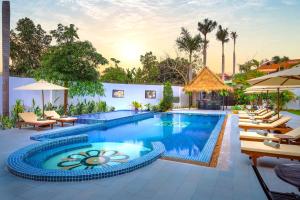 a pool at a resort with chairs and umbrellas at Sala Siem Reap Hotel in Siem Reap