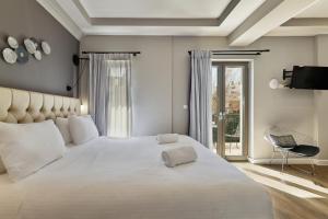 a bedroom with a large white bed and a balcony at Nival Luxury Suites in Chania