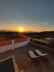 un coucher de soleil sur le toit d'un bâtiment avec deux bancs dans l'établissement Daphne's place, à Vívlos