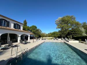 a swimming pool with chairs and a house at Hôtel La Bastide Saint Martin in Carcassonne