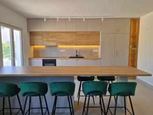 eine Küche mit einem großen Holztisch und grünen Stühlen in der Unterkunft Holiday Home Nino with amazing swimming pool in Slatine