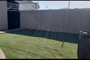 a backyard with a fence and green grass at Casa Maya in Mexicali