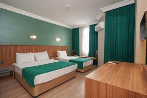 2 camas en una habitación de hotel con paredes verdes en ERGÜN OTEL, en Alanya