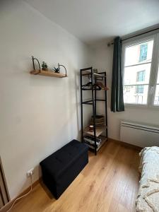 a room with a black ottoman in front of a window at La sapinière in Troyes
