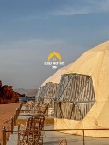 a row of tents with chairs in the desert at Golden mountains camp in Wadi Rum