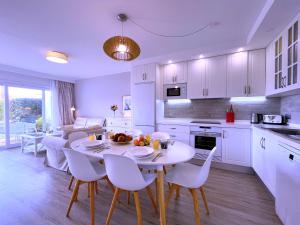 une cuisine avec une table et des chaises et une cuisine avec des armoires blanches dans l'établissement Tropicalidays Botanic Garden, à Puerto de la Cruz