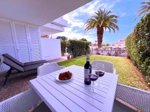 - une table blanche avec une bouteille de vin et un bol de fruits dans l'établissement Tropicalidays Botanic Garden, à Puerto de la Cruz