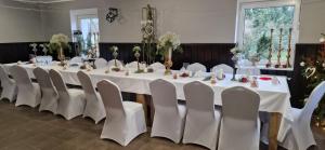 długi stół z białymi stołami i białymi krzesłami w obiekcie Zamek Bożejów w mieście Radomierowice