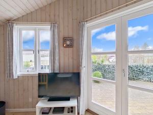 a living room with a tv and two windows at Holiday home Hemmet VI in Hemmet