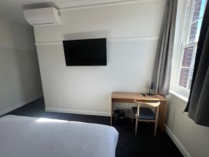 een slaapkamer met een bed en een bureau met een televisie bij Mortdale Hotel in Mortdale