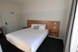 a bedroom with a large white bed and wooden headboard at Mortdale Hotel in Mortdale